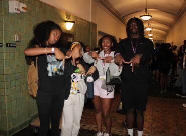Group of students making a block M sign with their hands.