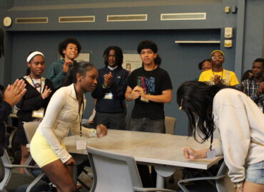 Group of students playing rock, paper, scissors in a classroom.