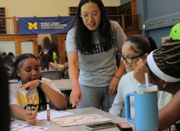 Students collaborating at a table on a whiteboard.