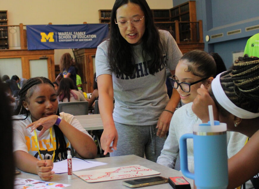 Students collaborating at a table on a whiteboard.