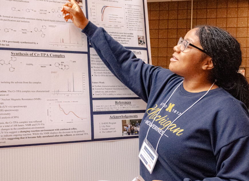Student presenting a poster board of their work.