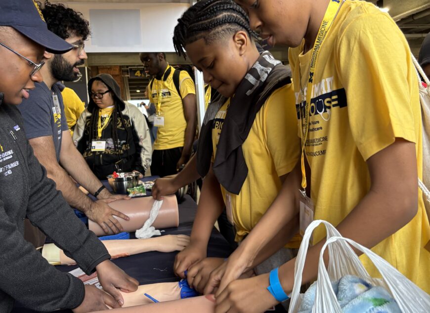 Students, wearing yellow shirts, learning with medical equipment.