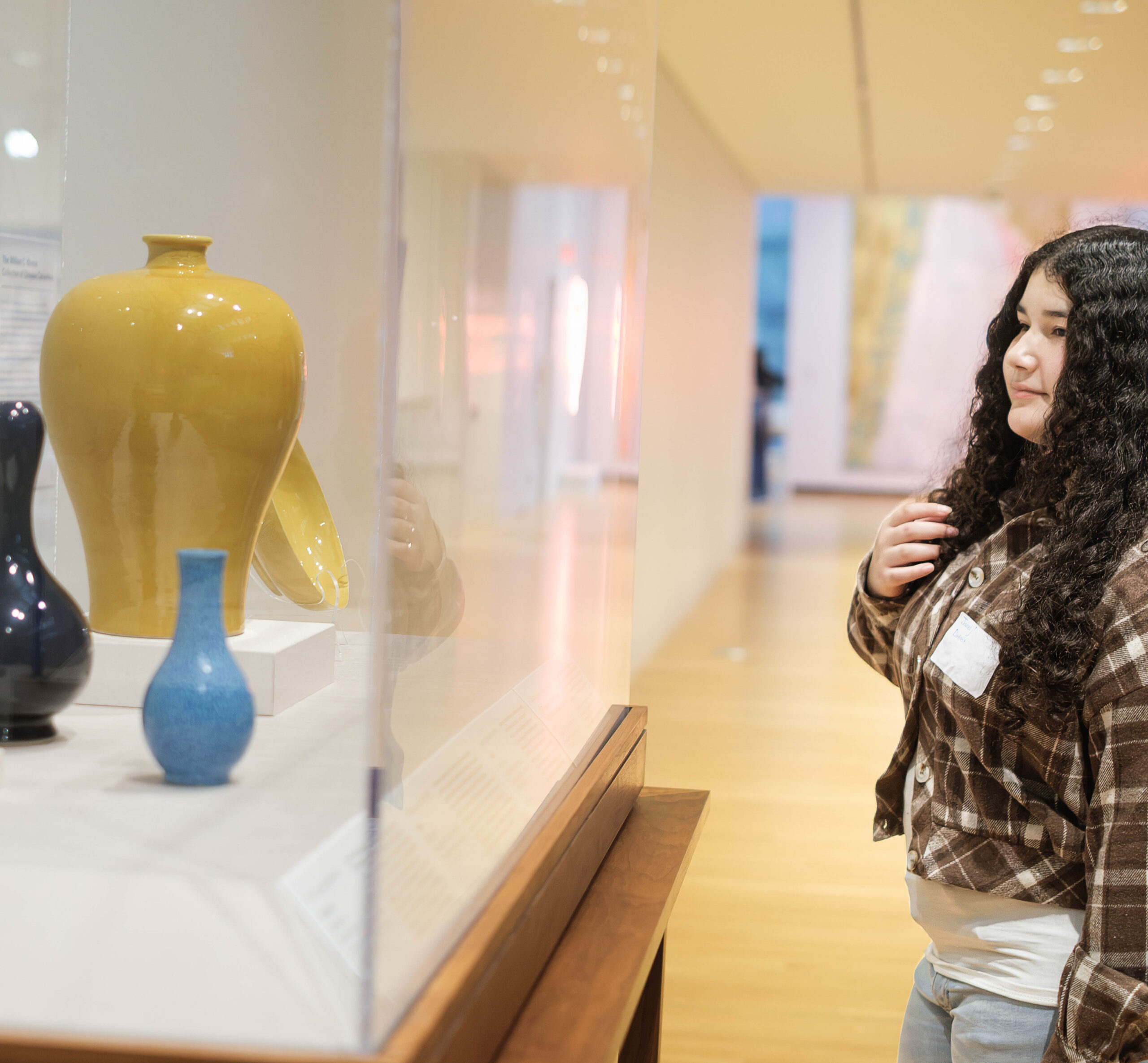 girl standing in art museum looking at vases